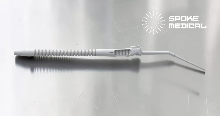 Zephyr microsuction handpiece on a brushed-steel surgical surface, angled tip and ribbed tubing